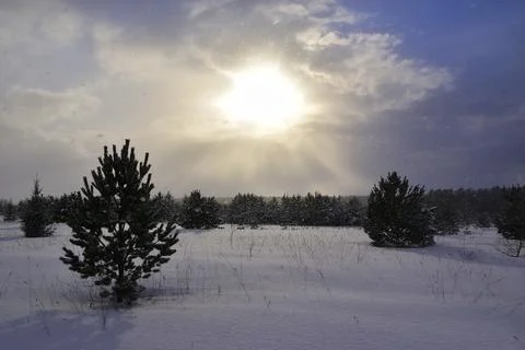 The sun peeps through a snow cloud on a winter day. Frontal weather change. Stock Photos