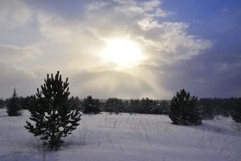 The sun peeps through a snow cloud on a winter day. Frontal weather change. Stock Photos