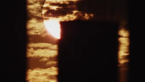 The sun peers through clouds and buildings, casting a dramatic light and Stock Footage 277074602