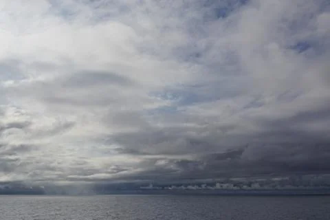 The sun pierces through gathering storm clouds over the Gulf of Alaska. Foto stock