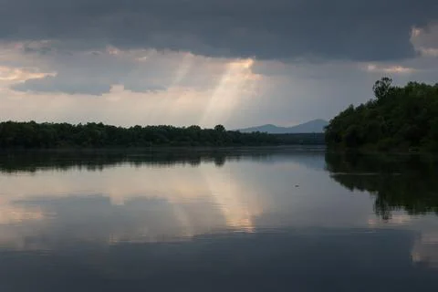 Sun ray piercing through clouds over river Stock Photos