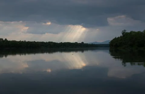 Sun ray piercing through clouds over river Stock Photos