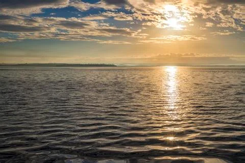 Sun rays beaming through picturesque clouds above the sea. Stock Photos