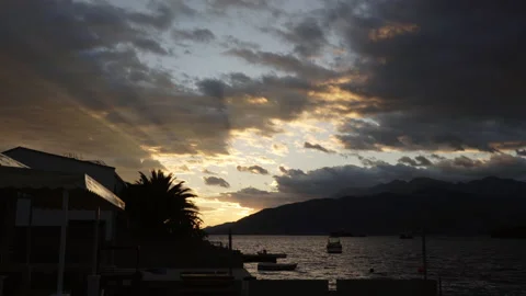Sun rays from behind mountains in Bay of Kotor shoot over waterfront Stock Footage 143906027