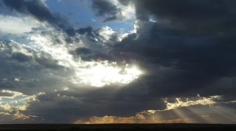 Sun rays beneath departing storm clouds at sunset, time lapse