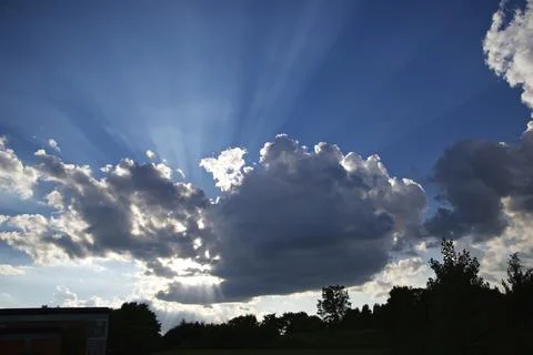 Sun rays with the blue cloudy sky in the background Stock Photos