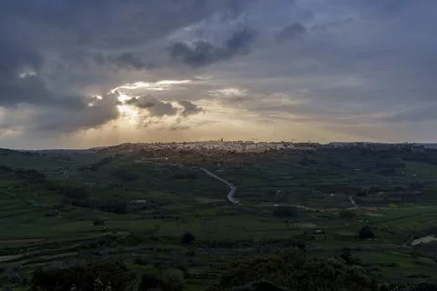 Sun Rays Break Through Storm Clouds over Patchwork Valleys at Dusk Stock Photos