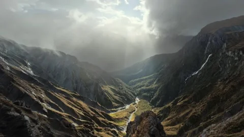 Sun Rays Breaking Through Clouds Over Rugged Mountains Stock Footage 315098802