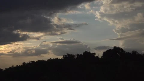 Sun rays breaking through clouds in the sky with tree silhouettes. Stock Footage 345669760