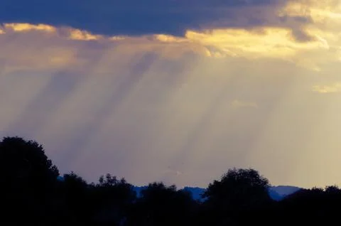 Sun rays breaking through the clouds of the evening sky Stock Photos