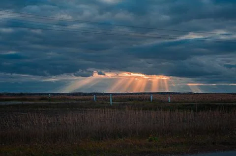 Sun rays breaking through the clouds over a mountain landscape Stock Photos