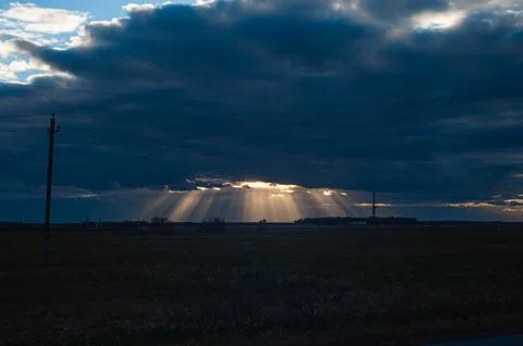 Sun rays breaking through the clouds over a mountain landscape Stock Photos