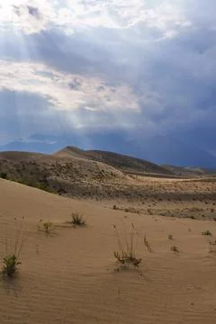 Sun rays breaking through clouds over desert dunes Foto stock