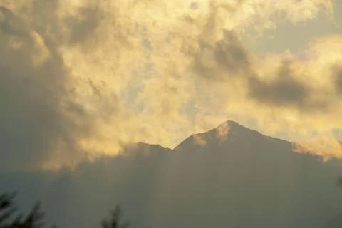Sun rays breaking through clouds over a mountain range Stock Photos