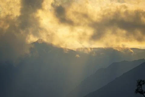 Sun rays breaking through clouds over a mountain range Stock Photos