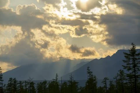 Sun rays breaking through clouds over a mountain range Foto stock