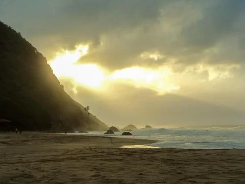 Sun rays breaking through the clouds on the beach near sunset Fotos de archivo