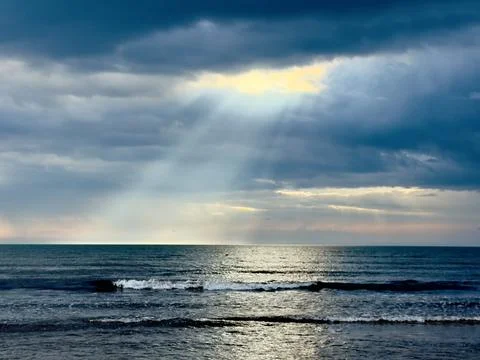 Sun Rays Breaking Through Clouds Over the Sea Stock Photos