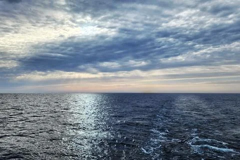 Sun Rays Breaking Through Clouds Over the Sea Stock Photos