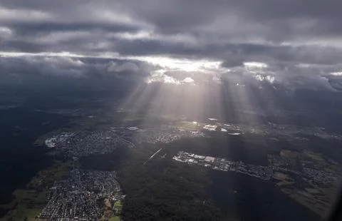 Sun rays breaking through clouds over a city landscape (God Rays) Stock Photos
