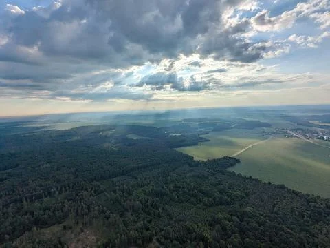 Sun rays breaking through clouds above green landscape aerial view from 写真素材