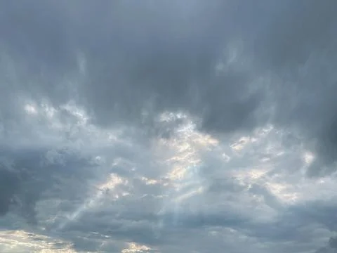 Sun rays breaking through dark clouds. Beautiful sky in the summer evening. Stock Photos