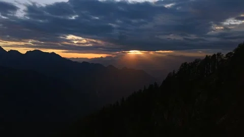 Sun rays breaking through dense clouds above dark Himalayan mountain ridges and Stock Footage 336590386