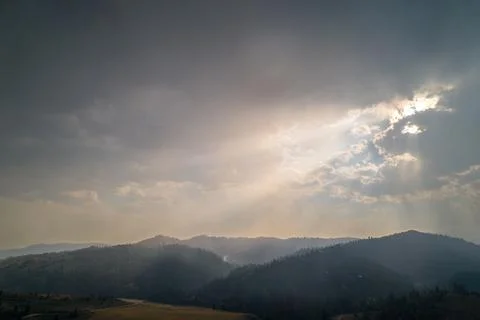 Sun Rays Breaking Through Misty Mountain Clouds at Dusk Stock Photos