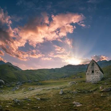 Sun rays breaking through the mountain at sunset. Family crypts on the mountain Stock Photos