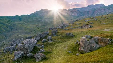 Sun rays breaking through the mountain at sunset. Stock Photos