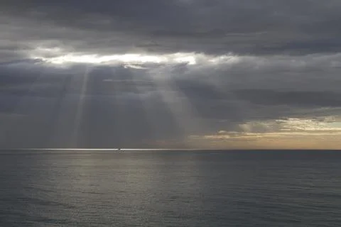 Sun rays breaking through the stauds over the sea. Stock Photos