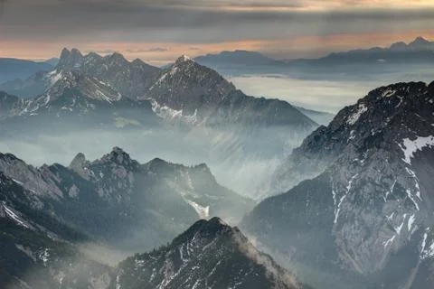 Sun rays burst through dark clouds over jagged Karavanke range Stock Photos