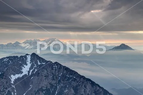 Sun rays burst through dark clouds in Karavanke and Kamnik Alps Stock Photos