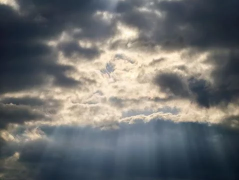 Sun rays cut through dark skies. Intense sunlight pierces ominous stormy cl.. 库存照片