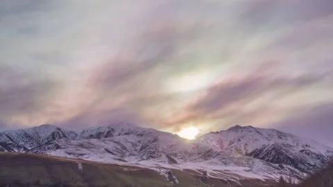 Sun rays emerge through the clouds in the mountains at sunrise. Video stock 244668903