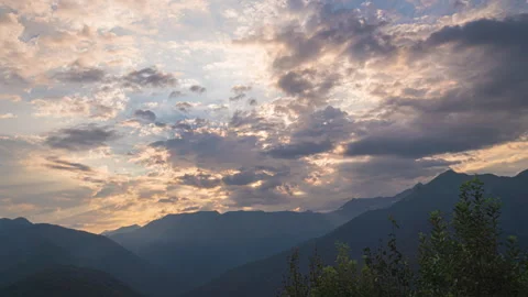 Sun rays emerge through the clouds in the mountains at sunset. Video stock 253096348