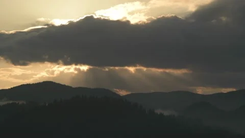 Sun rays emerging through the dark clouds passing over the mountain. Stock Footage 230652132