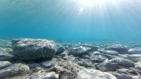 Sun rays entering a transparent rocky seabed Stock Footage 129840995