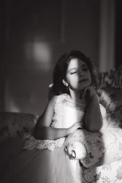 Sun rays fall on the face of little girl. Beautiful little model in studio with Stock Photos