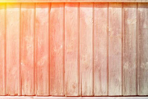 The sun rays fall on the old fence. Vertical wooden planks close up. Stock Photos