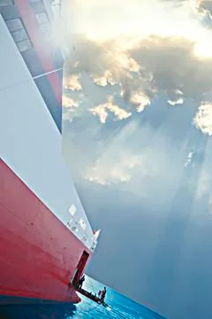 Sun rays fall over the big ship on the ocean Stock Photos