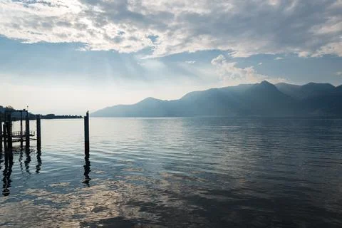 Sun rays filtering through the clouds over water. Lake Maggiore, Luino, Italy Stock Photos