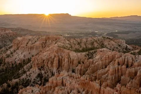 Sun Rays Flare Over Edge of Distant Mesa and Bryce Canyon Foto stock