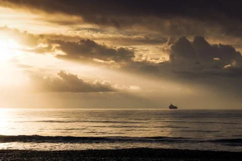 Sun rays flowing over ship on the horizon in Larnaca Stock Photos