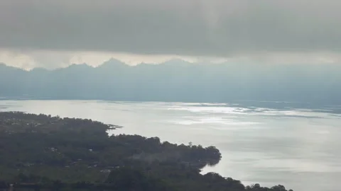 Sun Rays Illuminate Lake Batur Through Thick Cloud Cover Creating Atmospheric Hi Stock Footage 337017831