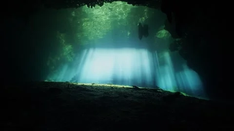 Sun rays illuminating a dark underwater cave creating a magical and ethereal Stock Footage 331524090