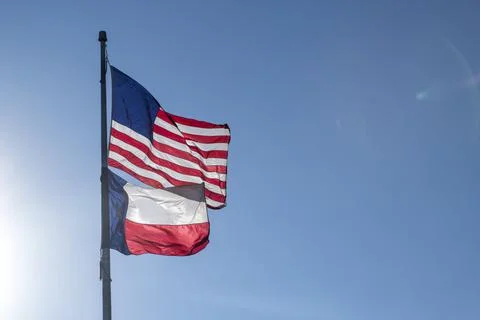 Sun Rays Lighting American Flag and Texas Flag Below on Flag Pole Blue Sky Stock Photos