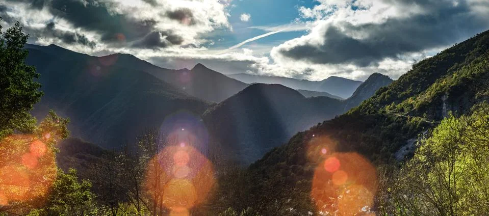Sun rays lighting through the clouds in high Pyrenees, sunrise, green valley Stock Photos
