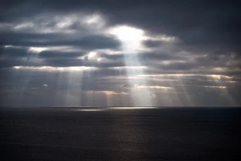 Sun rays make their way through dramatic clouds. Weather turns bad in the Stock Photos