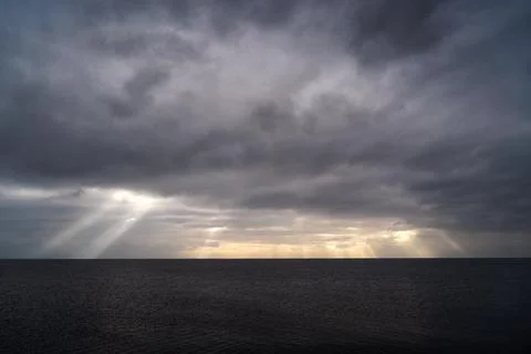 Sun rays make their way through dramatic clouds. Weather turns bad in the Stock Photos